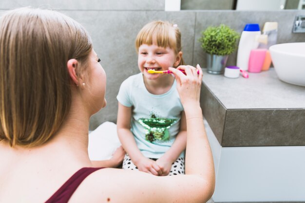 Madre cepillarse los dientes de niña