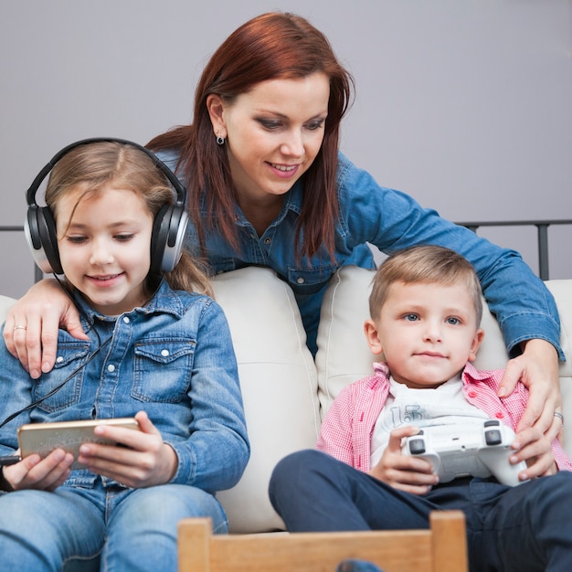 Madre cerca de niños usando tecnologías