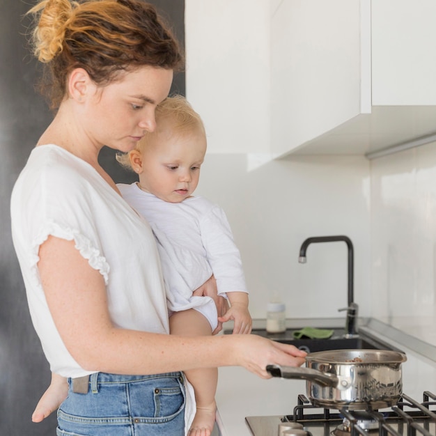 Foto gratuita madre cocinando mientras sostiene a la niña