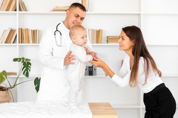 Madre cogidos de la mano del bebé en el examen médico