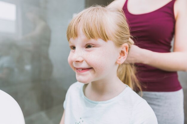 La madre de la cosecha que pone el pelo de la muchacha sonriente