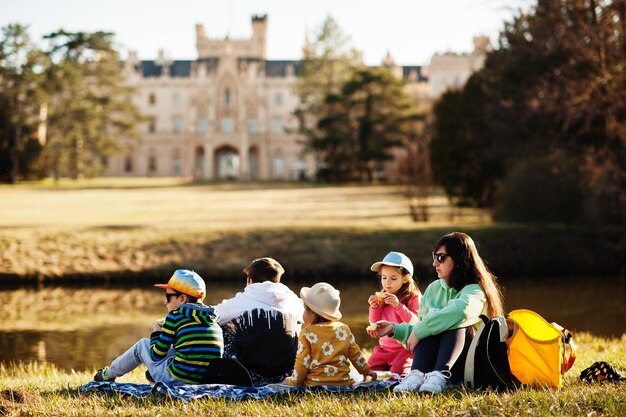 Madre con cuatro hijos haciendo un picnic cerca de la libra en el parque Lednice contra el castillo República Checa