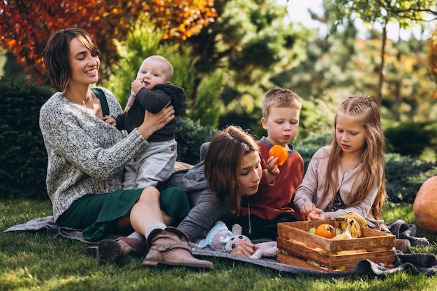 Madre con cuatro hijos haciendo un picnic en el patio trasero