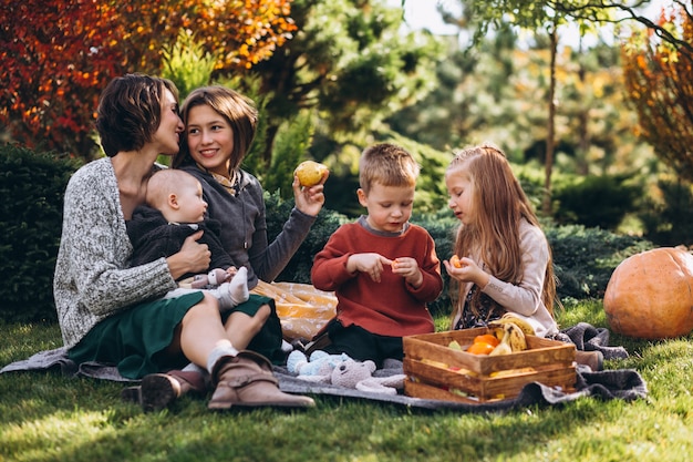 Madre con cuatro hijos haciendo un picnic en el patio trasero