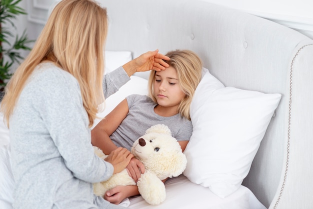 Madre cuidadosa que controla la temperatura de la hija