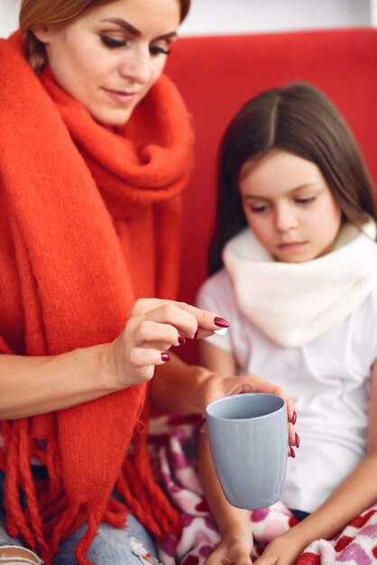 Madre le da té caliente a su hija enferma