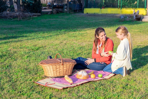 Foto gratuita madre dando una manzana a su hija en el parque