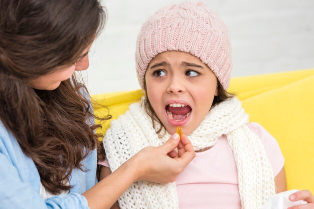 Madre dando una pastilla a su hija