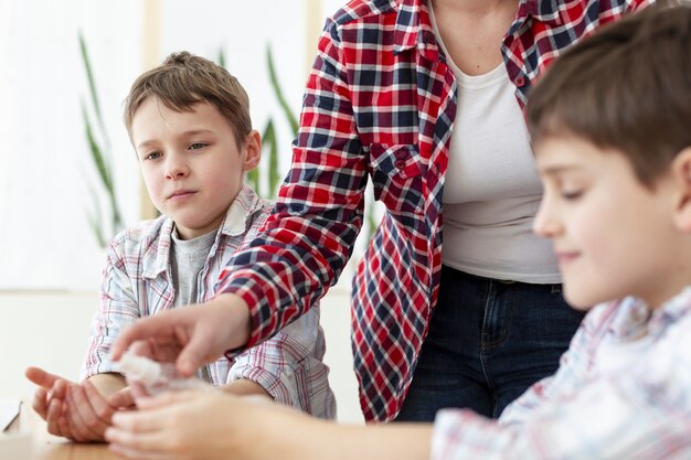 Madre desinfectando las manos de sus hijos