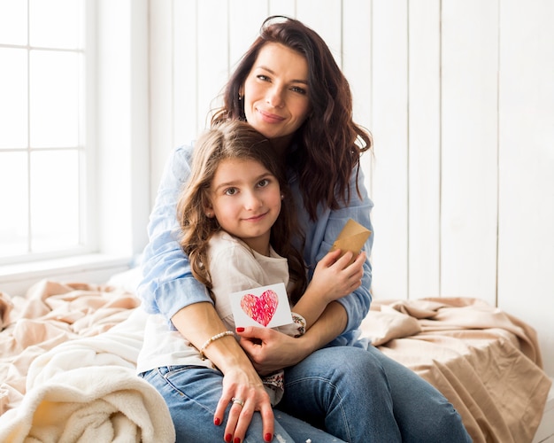 Foto gratuita madre con dibujo de corazón abrazando a hija