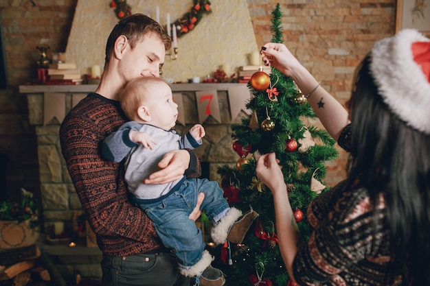 Madre distrayendo al bebé con un adorno de navidad mientras el padre lo sostiene en brazos