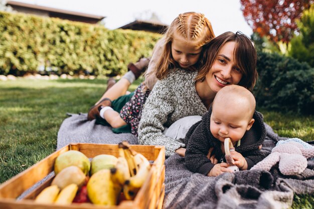 Madre con dos hijos haciendo un picnic en un patio trasero