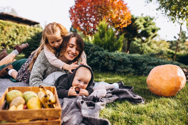 Madre con dos hijos haciendo un picnic en un patio trasero