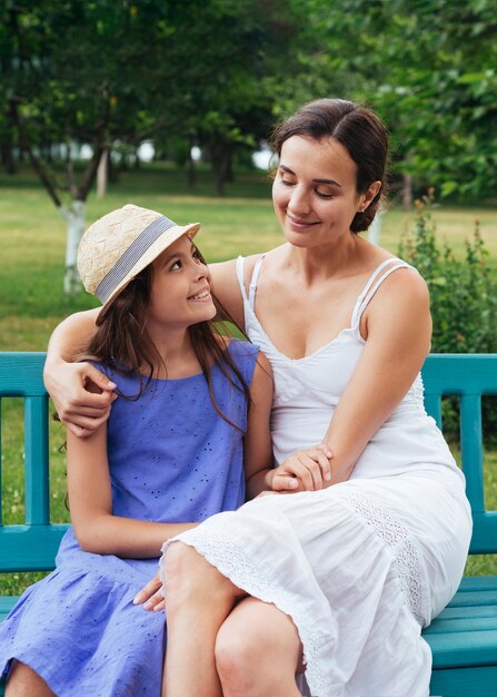 Madre e hija abrazando en el banco al aire libre