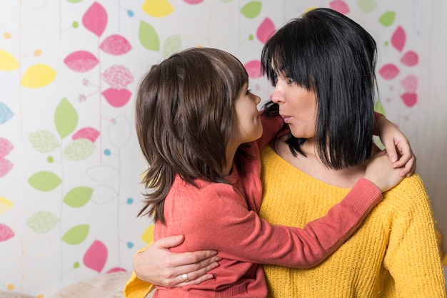 Madre e hija abrazando y haciendo pucheros en los labios.