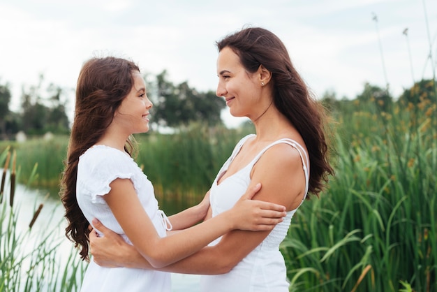 Madre e hija abrazando por el lago