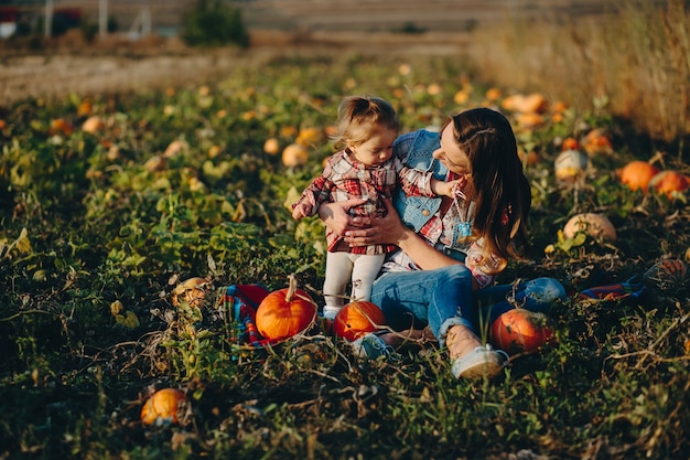 Madre e hija en un campo con calabazas, víspera de Halloween