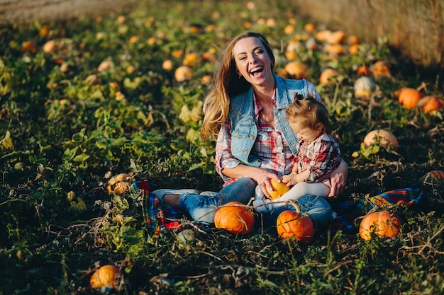 Madre e hija en un campo con calabazas, víspera de Halloween