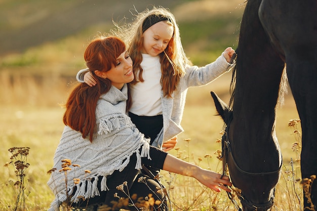 Madre e hija en un campo jugando con un caballo