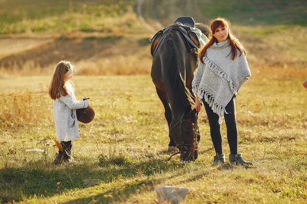 Madre e hija en un campo jugando con un caballo