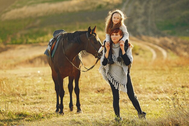 Madre e hija en un campo jugando con un caballo