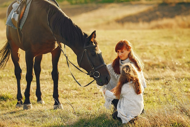 Madre e hija en un campo jugando con un caballo