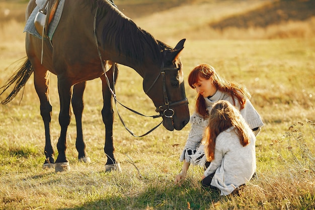 Madre e hija en un campo jugando con un caballo