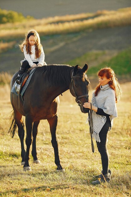 Madre e hija en un campo jugando con un caballo