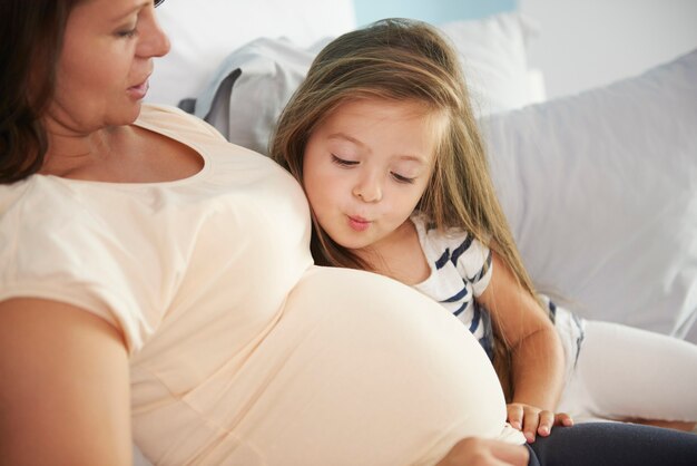 Madre e hija cantan al abdomen de su mamá