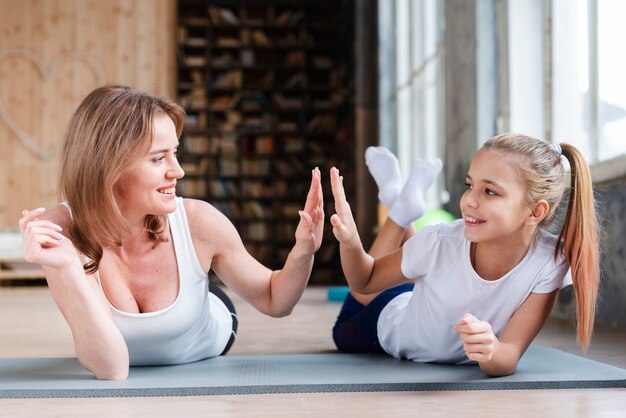 Madre e hija chocando las manos con colchonetas de yoga