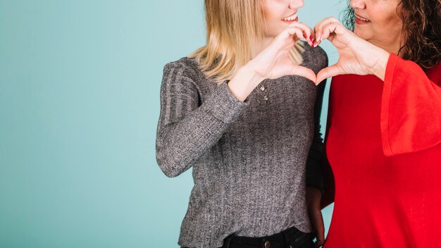 Madre e hija de la cosecha que hacen gesto del corazón