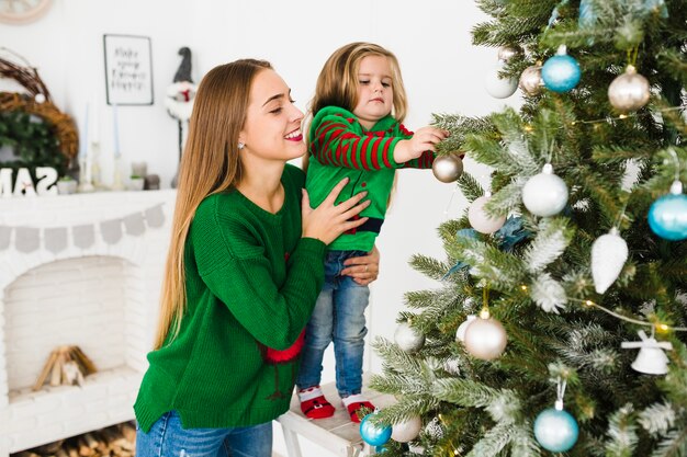 Madre e hija decorando árbol de navidad