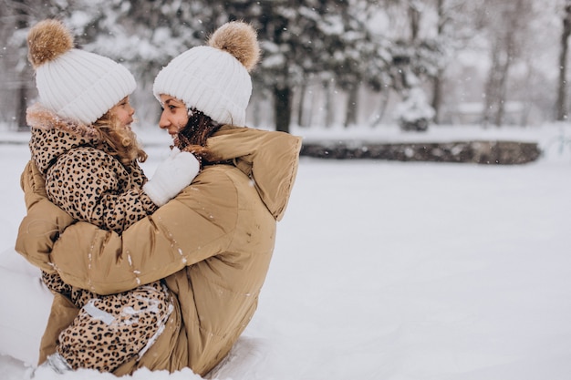 Madre e hija divirtiéndose en el parque lleno de nieve