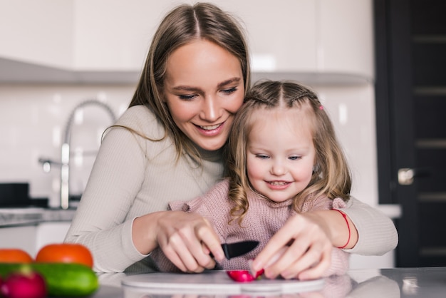 Madre e hija están preparando la ensalada de verduras