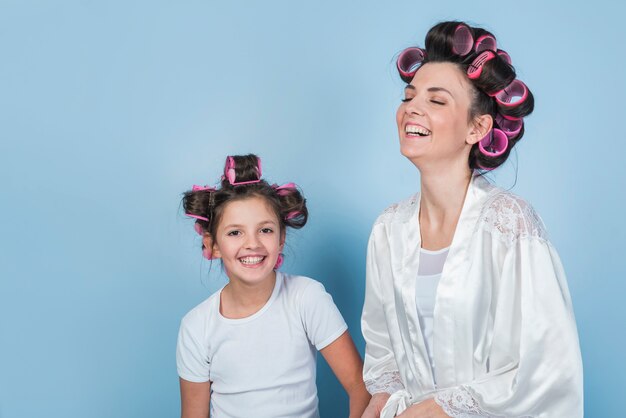 Madre e hija felices en la sonrisa de los bigudíes