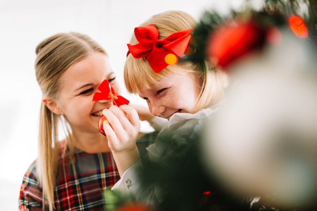 Madre e hija feliz enfrente de árbol de navidad