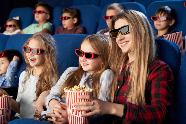 Madre e hija en gafas 3d comiendo palomitas de maíz en el cine