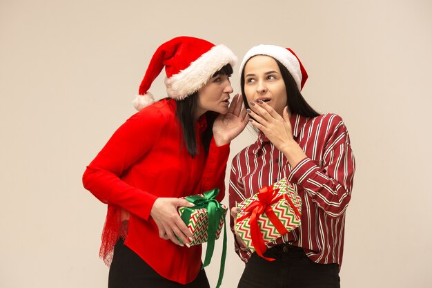 Madre e hija con gorro de Papá Noel y caja de regalo