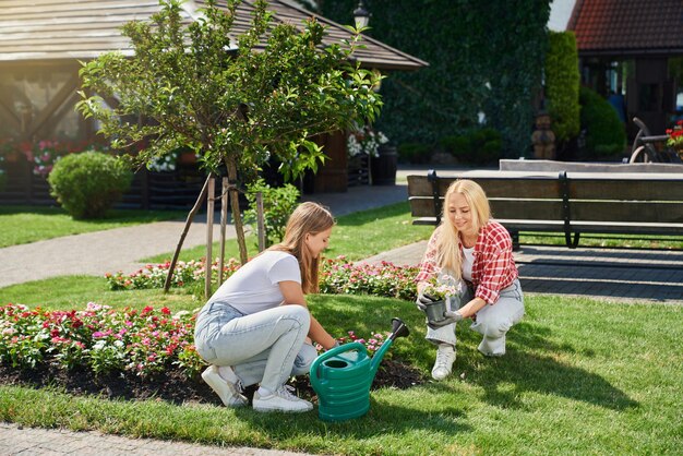 Madre e hija en guantes plantando flores en el jardín