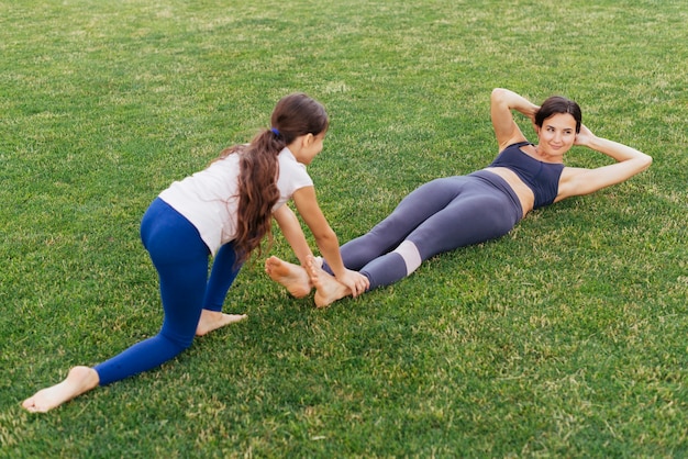 Madre e hija haciendo ejercicio en la hierba verde