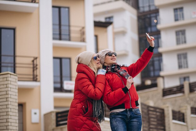 Madre e hija haciendo selfie afuera en invierno