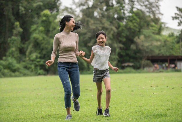 Madre e hija jugando y corriendo por el parque