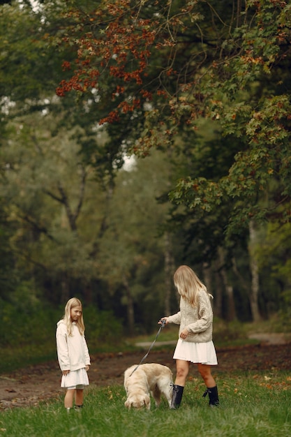 Madre e hija jugando con perro. Familia en el parque de otoño. Concepto de mascota, animal doméstico y estilo de vida. Otoño.