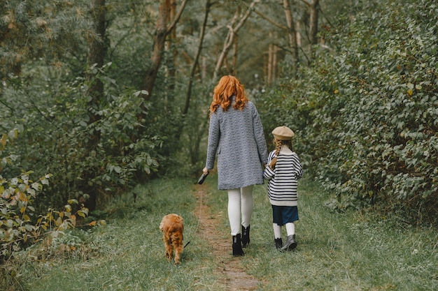 Madre e hija jugando con perro. Familia en el parque de otoño. Concepto de mascota, animal doméstico y estilo de vida. Otoño.