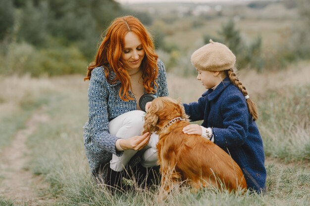 Madre e hija jugando con perro. Familia en el parque de otoño. Concepto de mascota, animal doméstico y estilo de vida. Otoño.