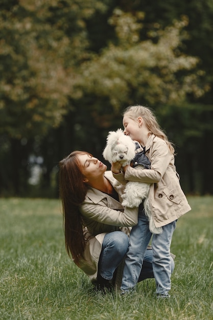 Madre e hija jugando con perro. Familia en el parque de otoño. Concepto de mascota, animal doméstico y estilo de vida.