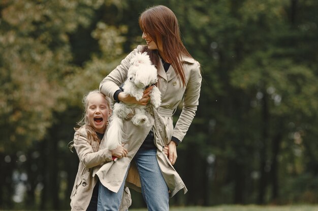 Madre e hija jugando con perro. Familia en el parque de otoño. Concepto de mascota, animal doméstico y estilo de vida.