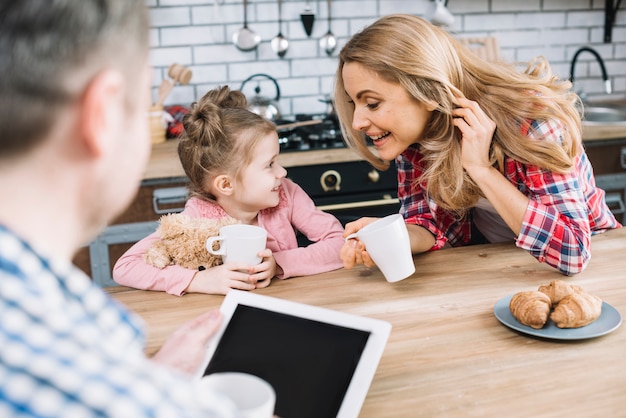 Foto gratuita madre e hija juguetonas que se miran que sostienen la taza de café