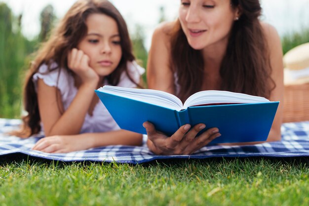 Madre e hija leyendo un libro al aire libre