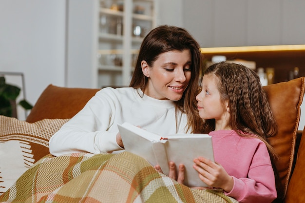 Madre e hija leyendo un libro en casa